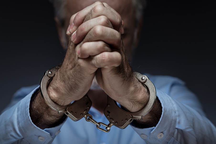 The image depicts a senior person with hands clasped, wrists bound in handcuffs. This imagery emphasizes the potential harm of excessive force by law enforcement against seniors.